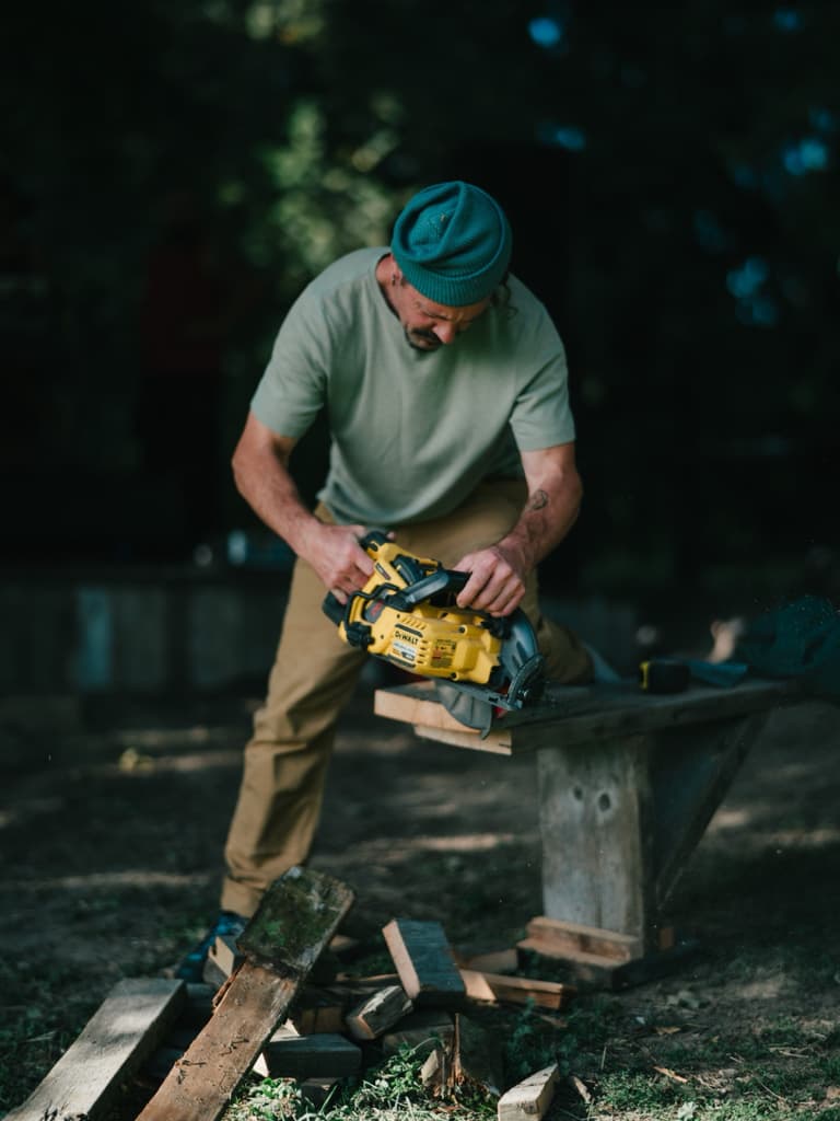 A man cutting timber with a chainsaw in a shaded yard on Salt Spring Island