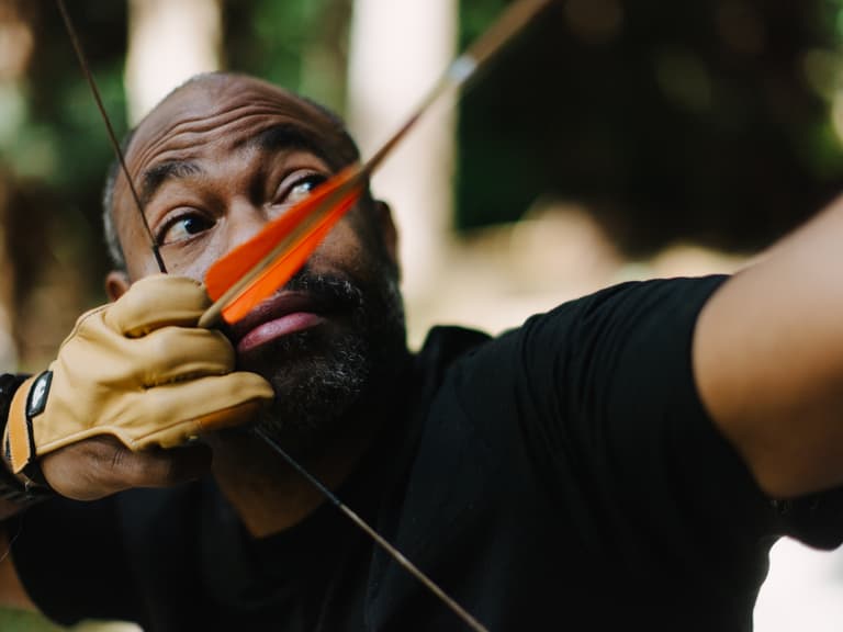 Christopher Applewhaite at full draw, orange fletching held at his cheek