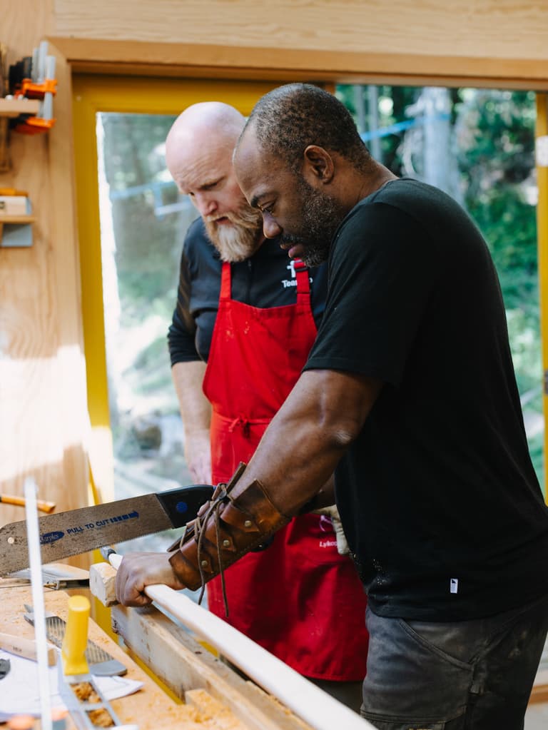 Christopher Applewhaite guiding a participant at the bench during a bow making workshop