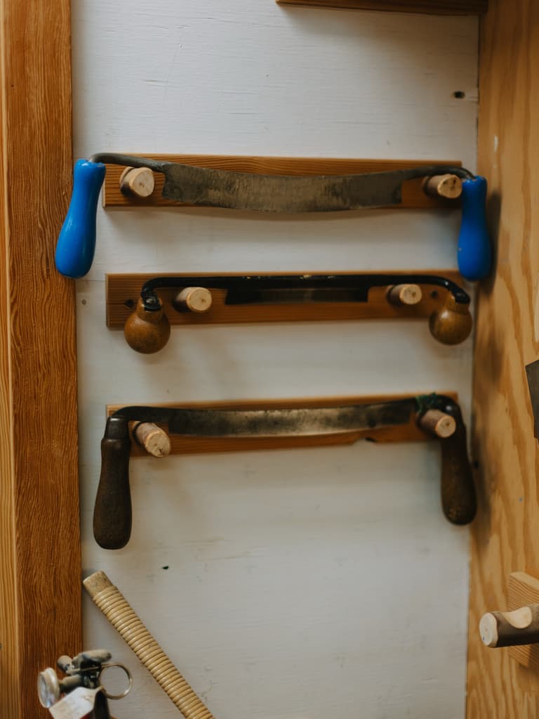 Three drawknives hanging in a row on the bow workshop wall